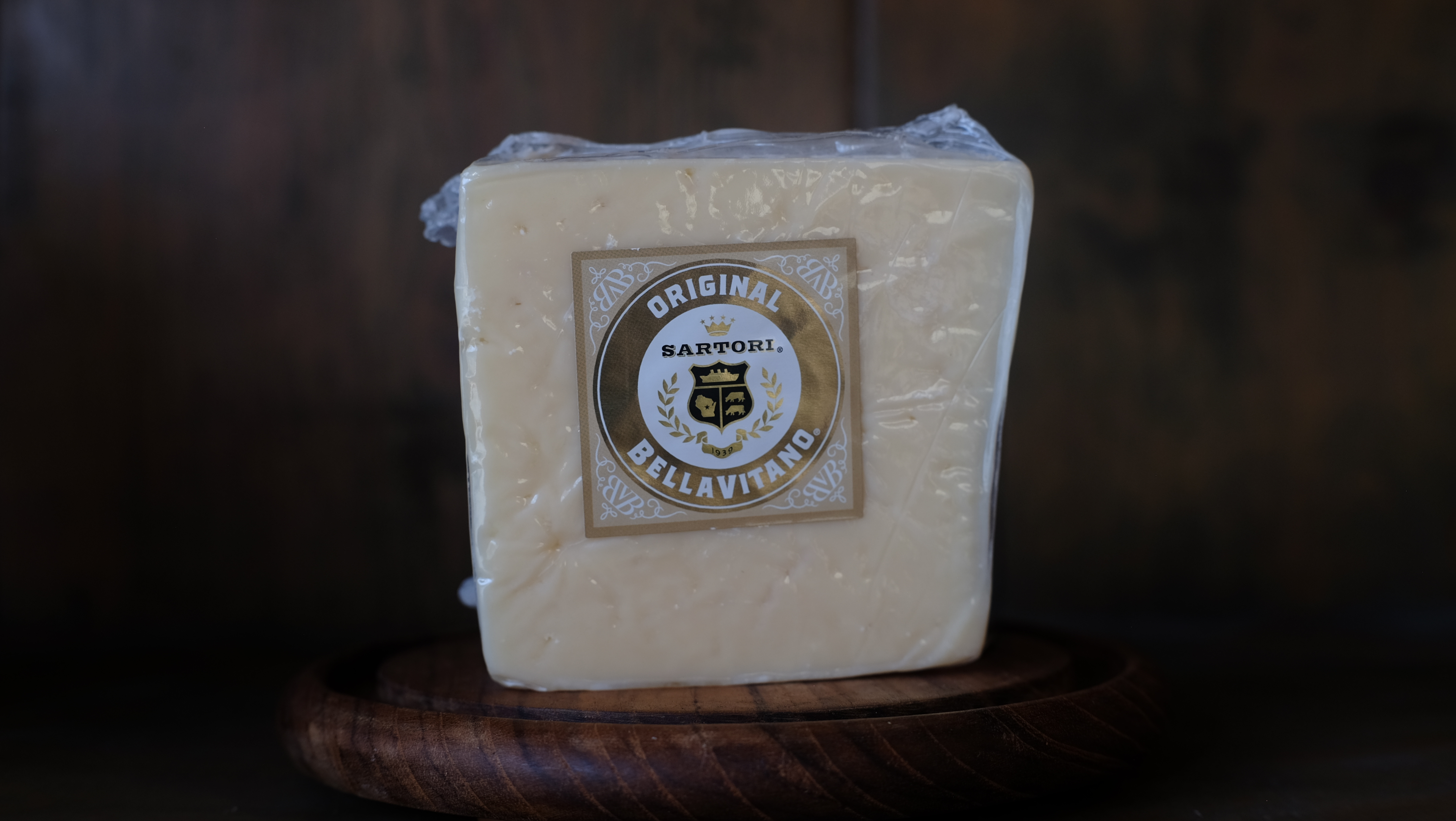 Wedge of BellaVitano cheese showing crystalline texture on a board