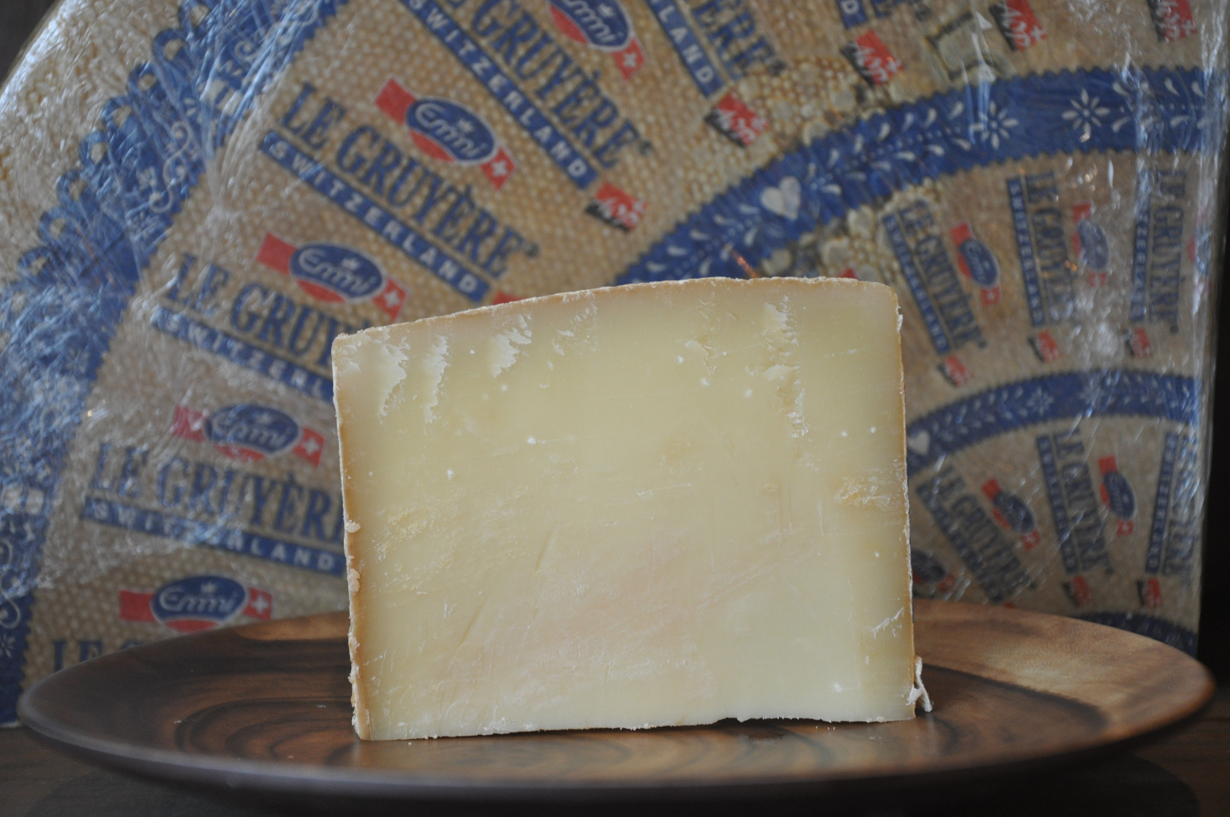 Wedge of aged Le Gruyere Swiss cheese on a wooden board
