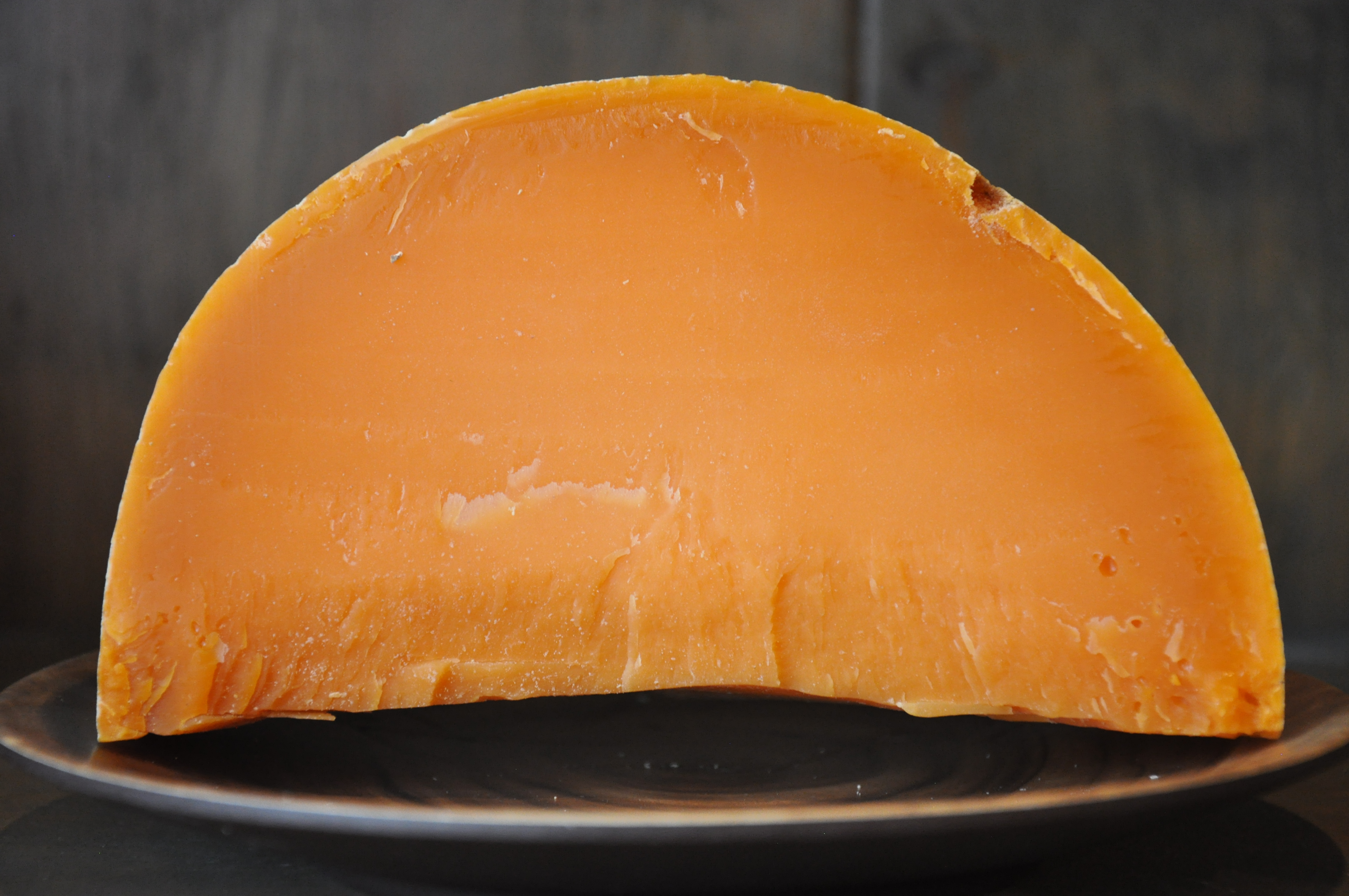 Wedge of cave-aged Mimolette showing bright orange interior
